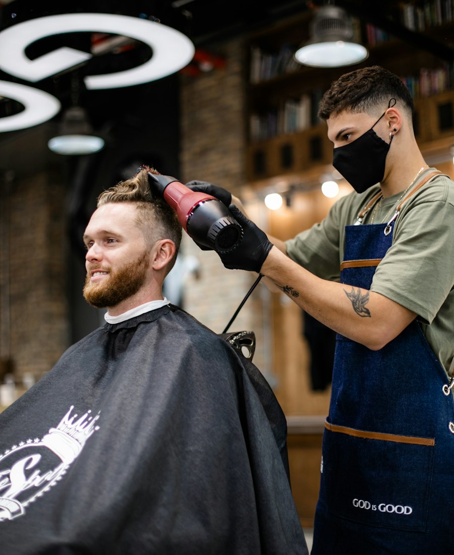 A barber in a denim apron styling a client's hair