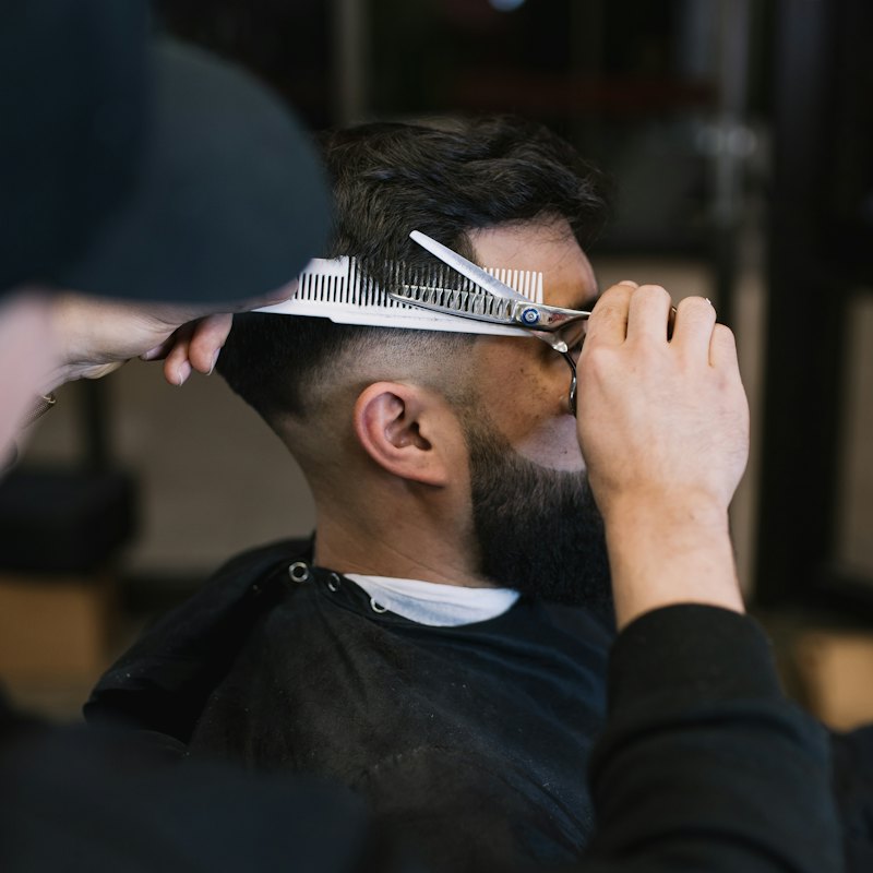 A barber cutting a client's hair with scissors