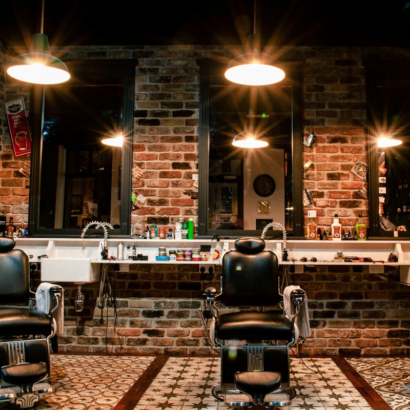 A black leather barber chair in front of a brick wall
